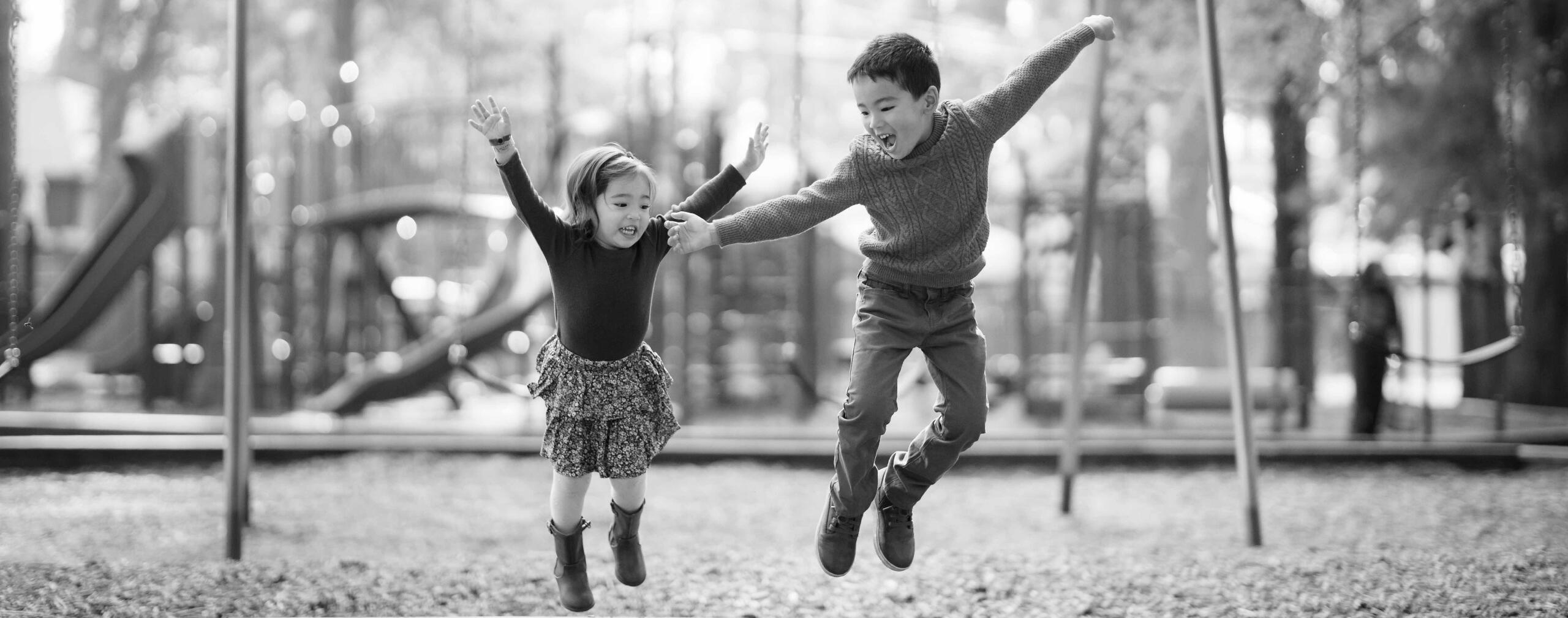 Two children leap together at a playground