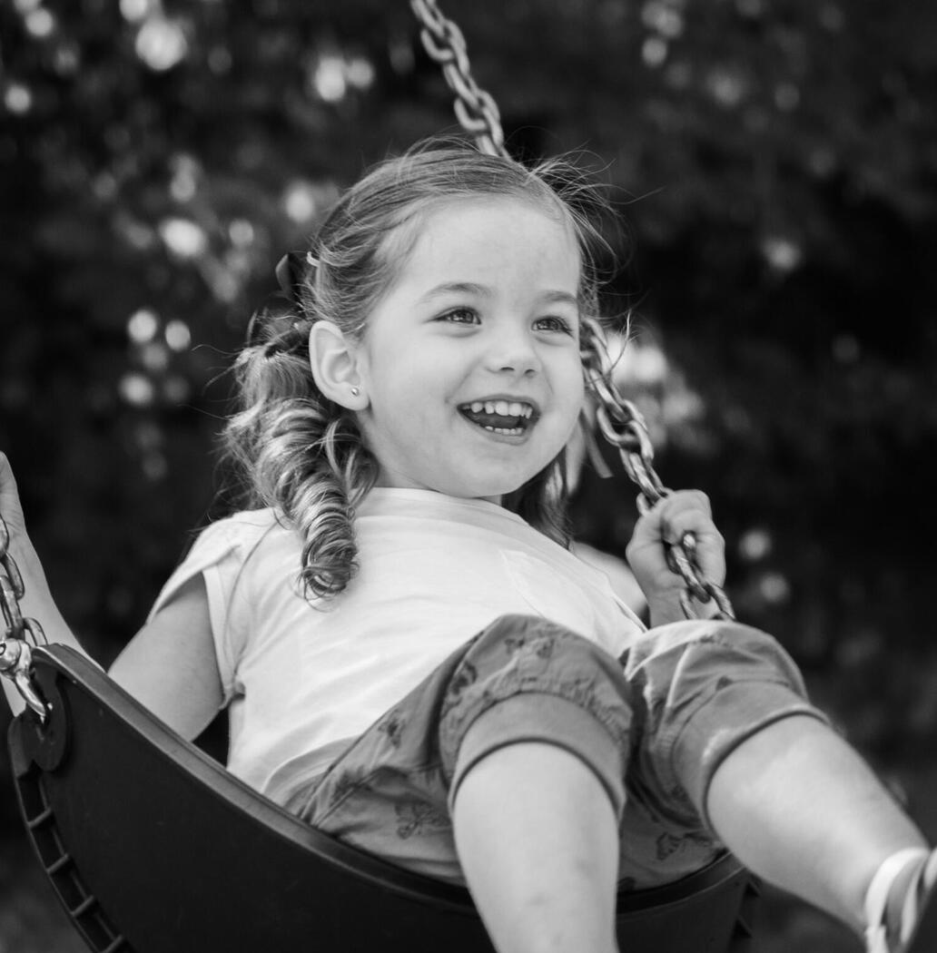 A smiling child swings toward the camera