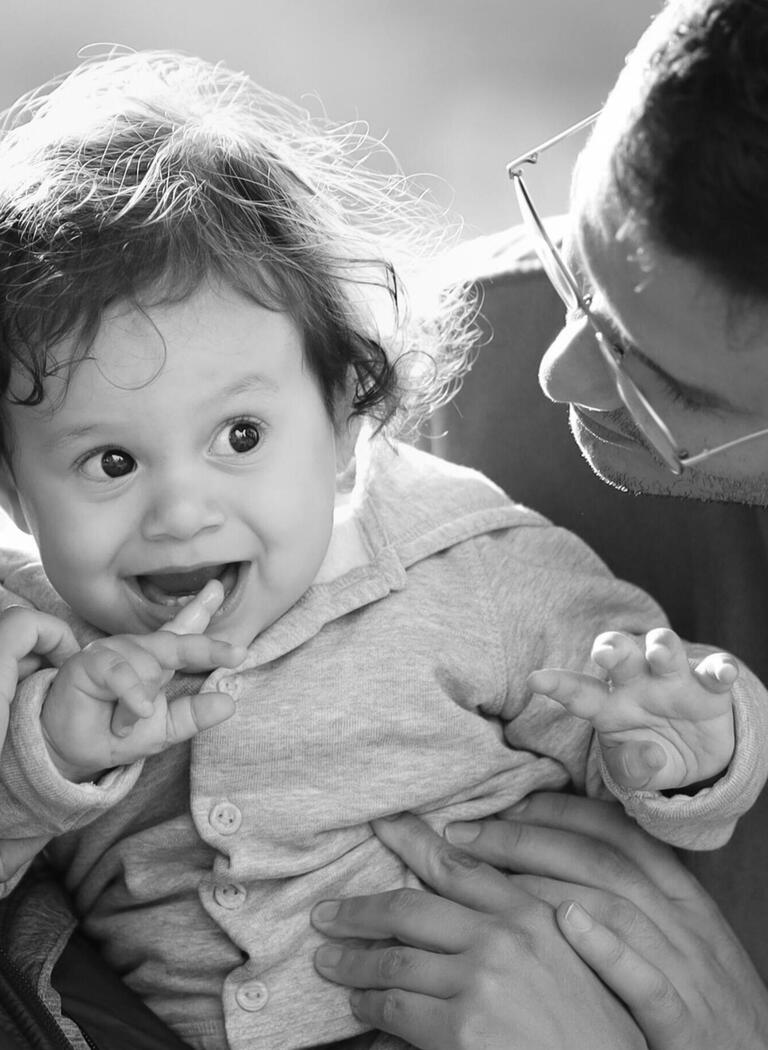 A laughing baby looks toward a parent