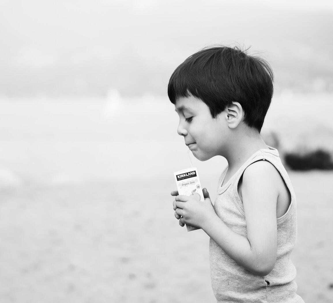 A child pauses with a small drink in hand